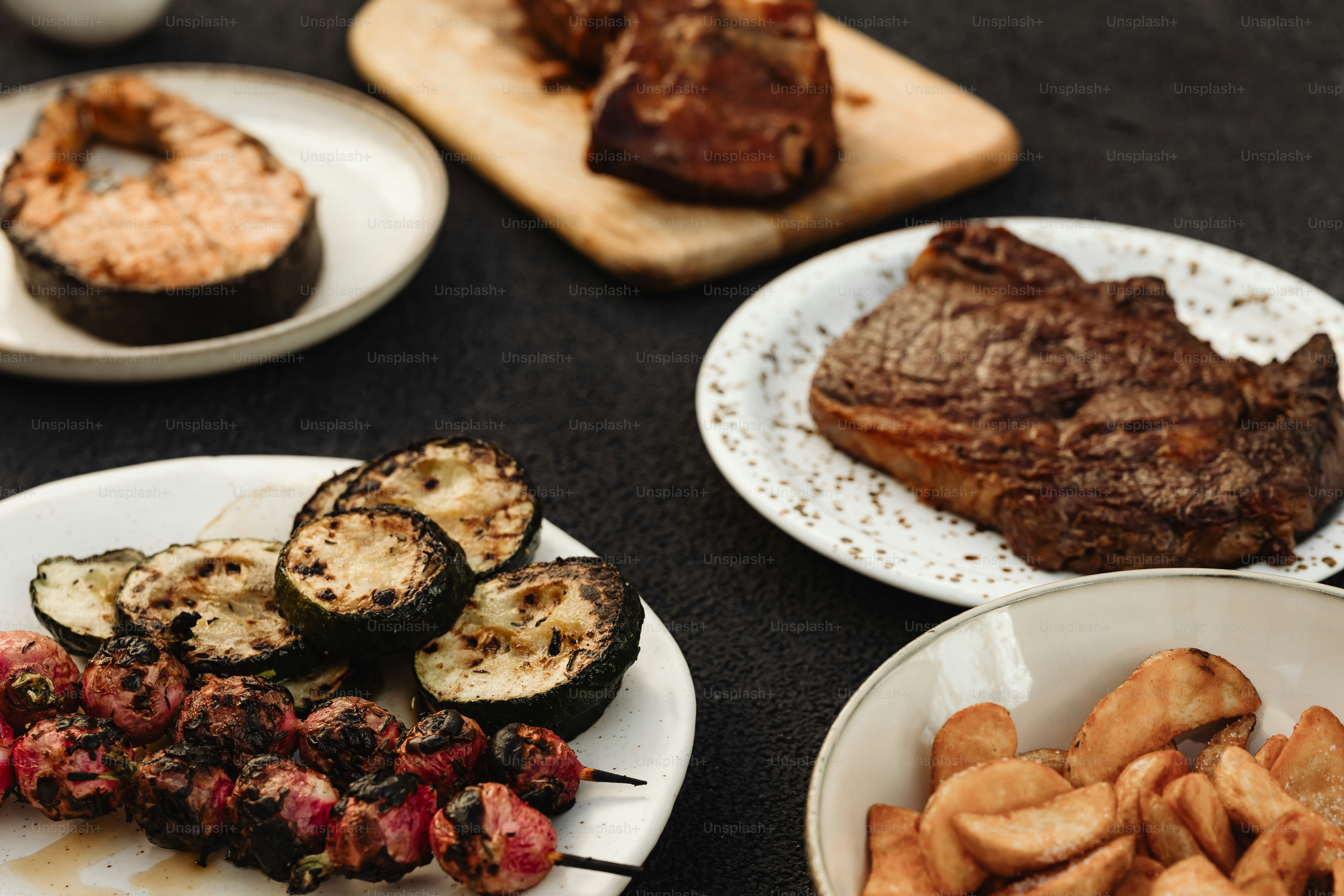 a table topped with plates of food and meat