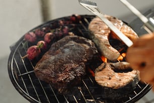 a person grilling steaks and vegetables on a grill