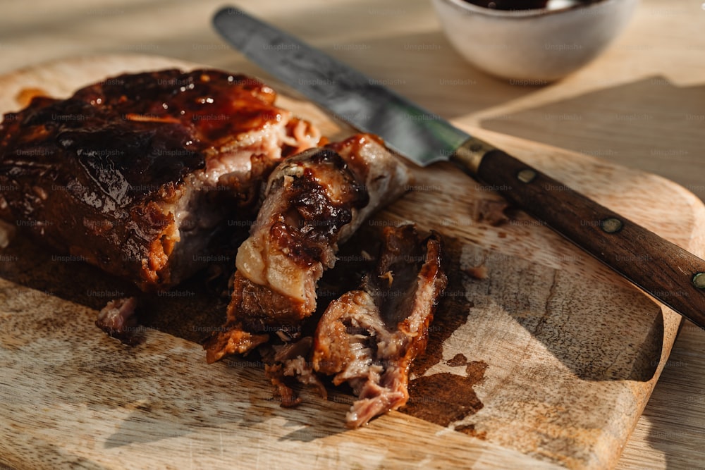 una tabla de cortar de madera cubierta con carne y un cuchillo