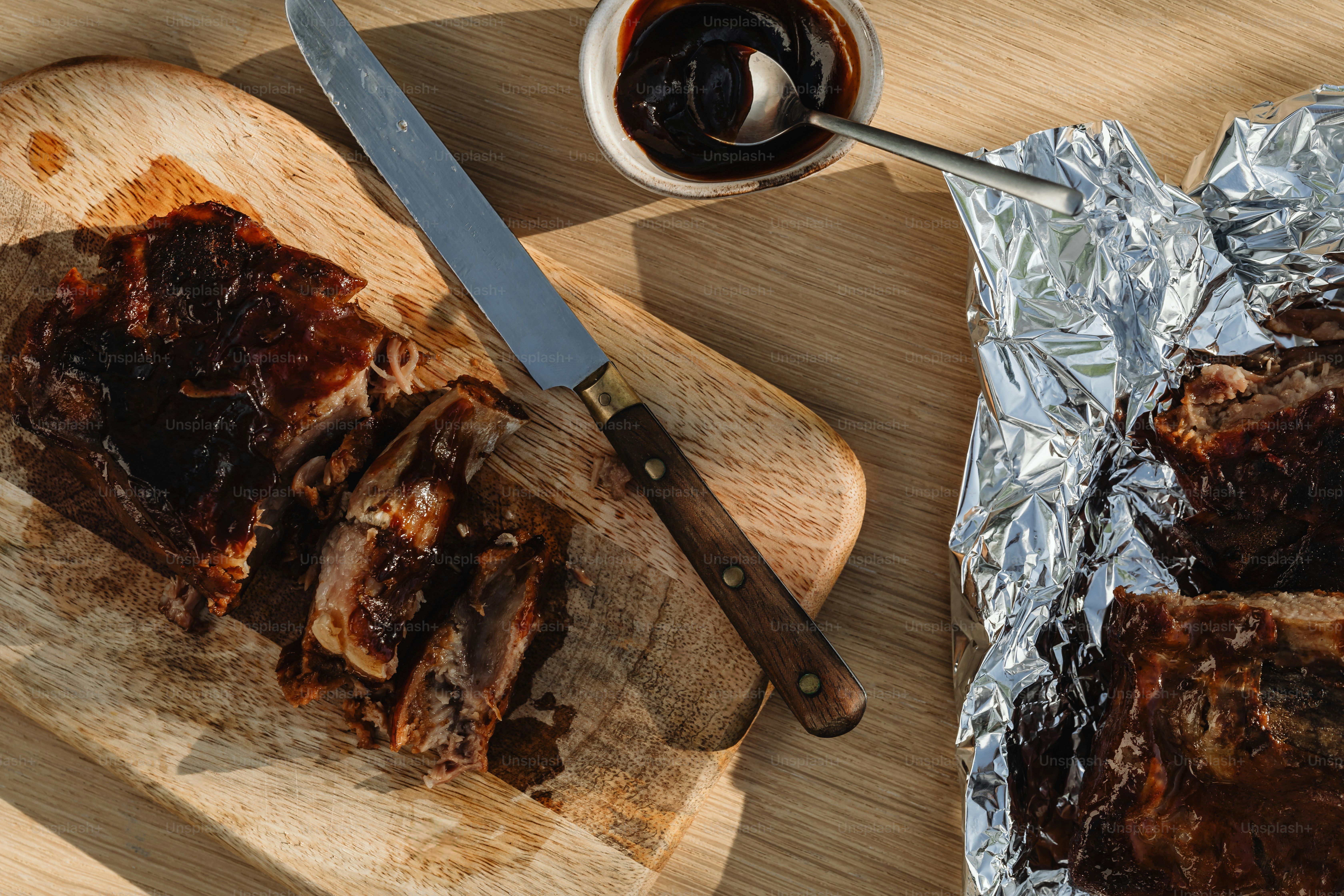 una tabla de cortar de madera cubierta con carne junto a un cuchillo