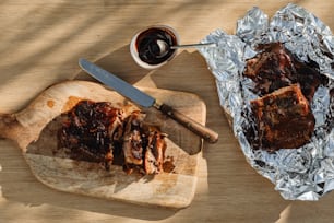 a wooden cutting board topped with ribs next to a knife