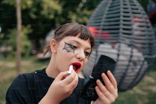 얼굴에 화장을 한 여자가 휴대폰을 사용하고 있다
