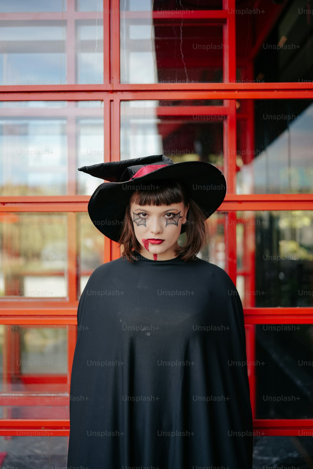 a woman wearing a black cape and a black hat