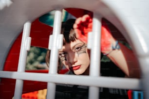 a woman with eyeliners and eye makeup looking through a fence