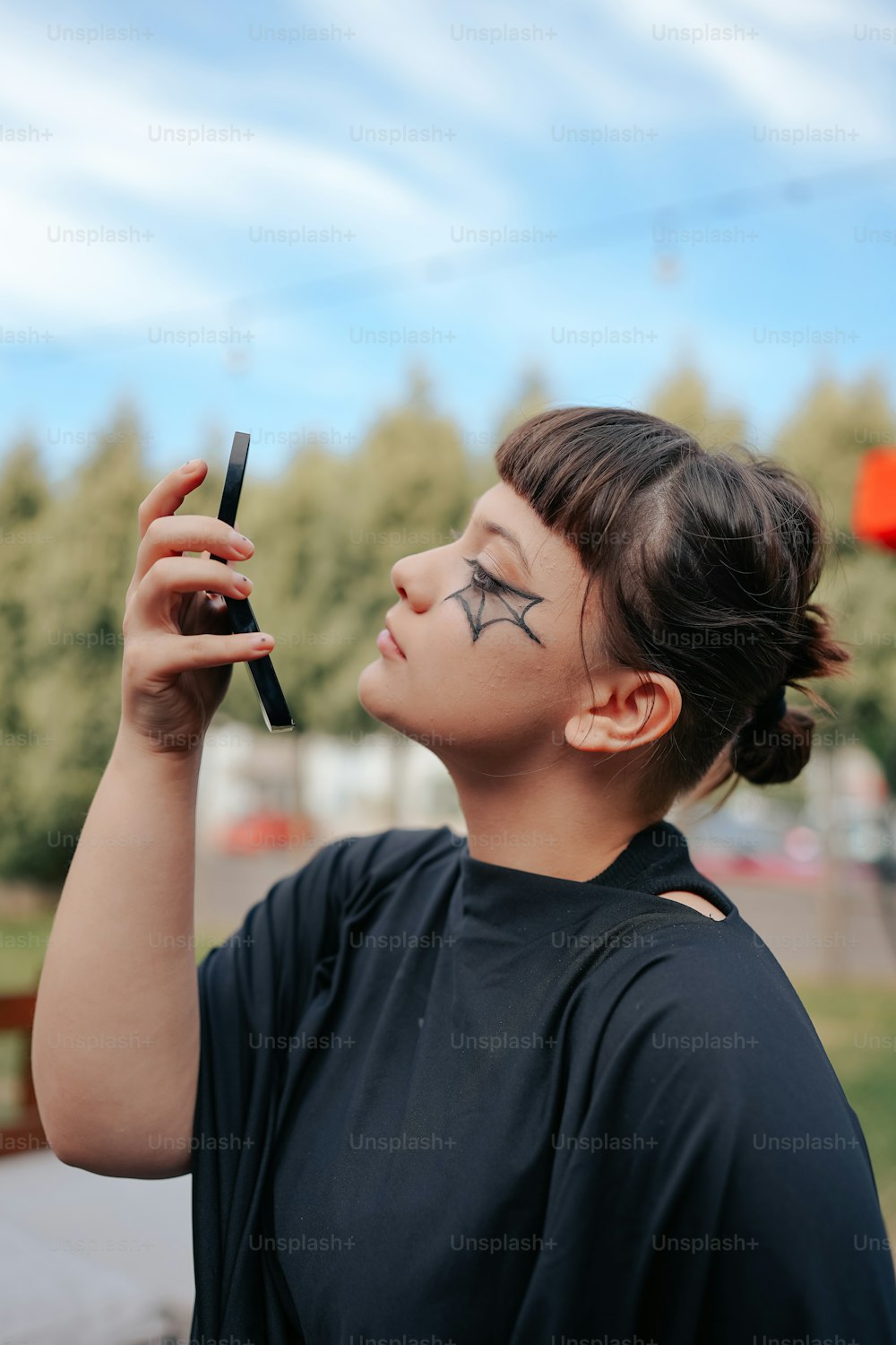 a woman with black makeup holding a cell phone