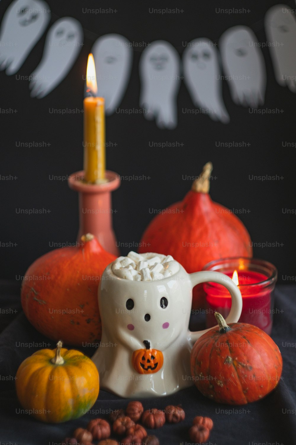 a white mug with a ghost on it surrounded by pumpkins and nuts