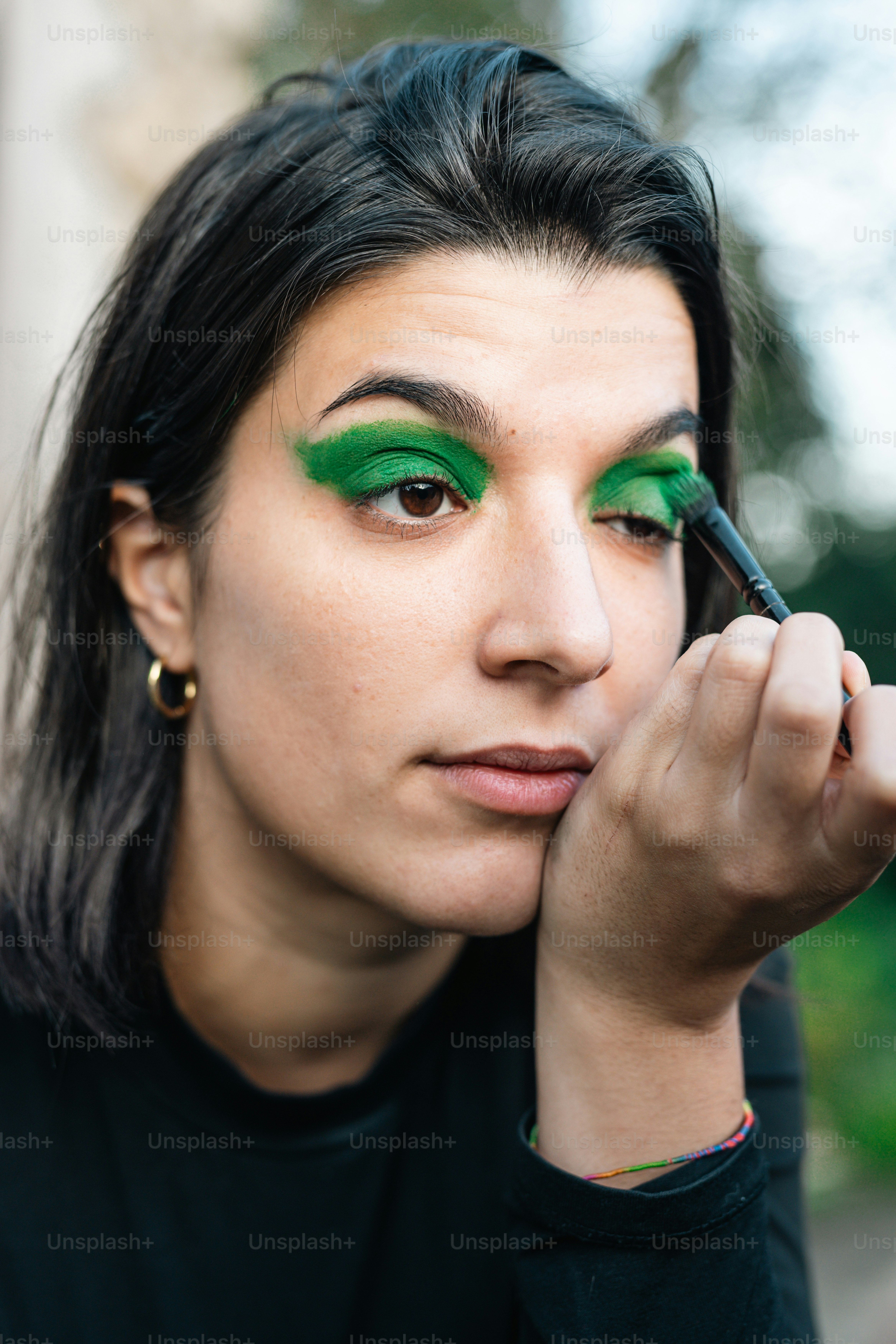 Une femme avec des eye-liners verts et une chemise noire