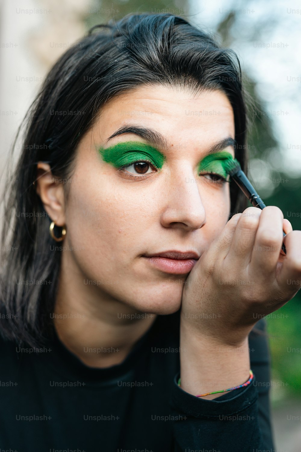 a woman with green eyeliners and a black shirt