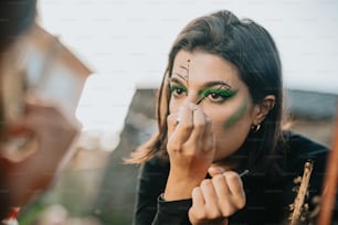 a woman with green makeup is putting on makeup