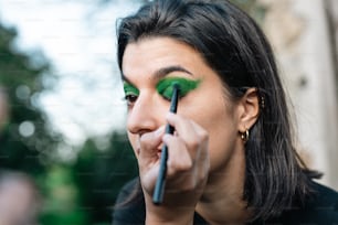 a woman with green eye makeup doing makeup