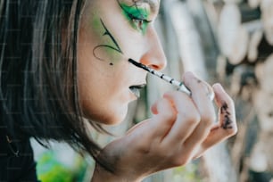 a woman with face paint is holding a brush