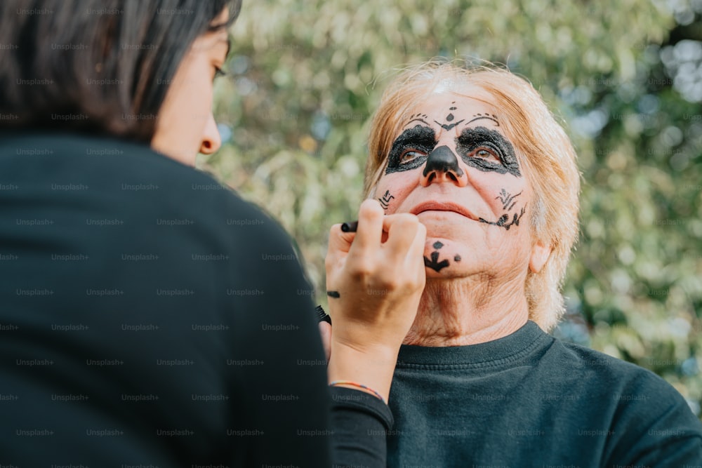 a woman is putting makeup on a man's face