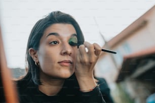 a woman is doing makeup on her face