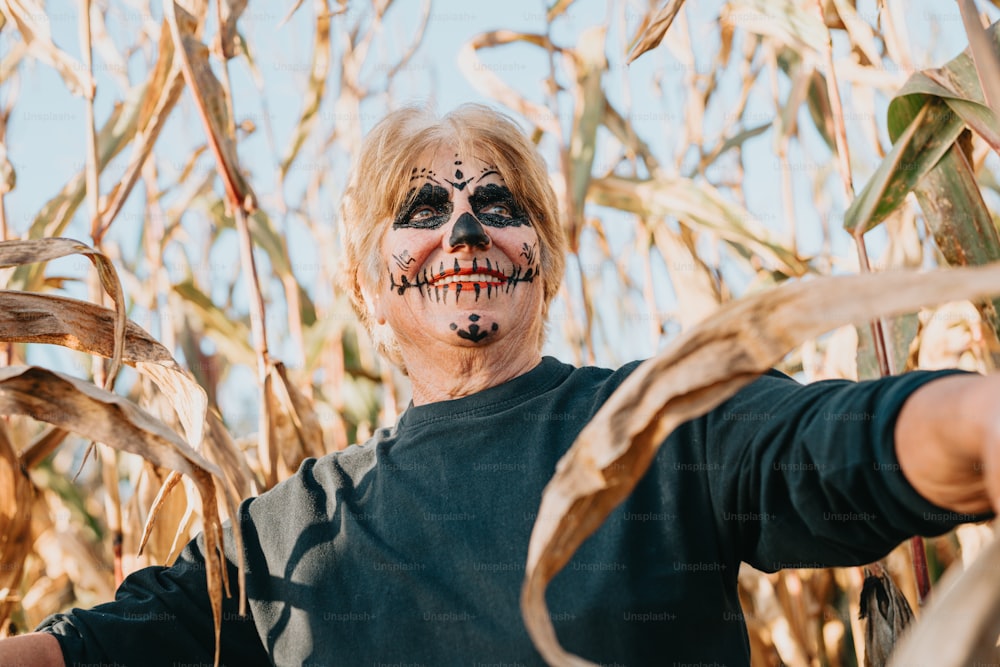 um homem com o rosto pintado em pé em um campo de milho