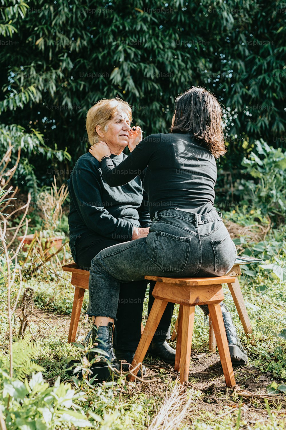 uma mulher sentada em cima de um banquinho de madeira ao lado de outra mulher