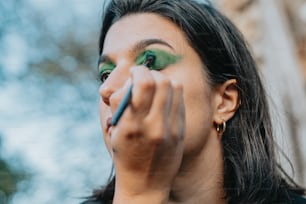 a woman with green eye makeup holding a pencil