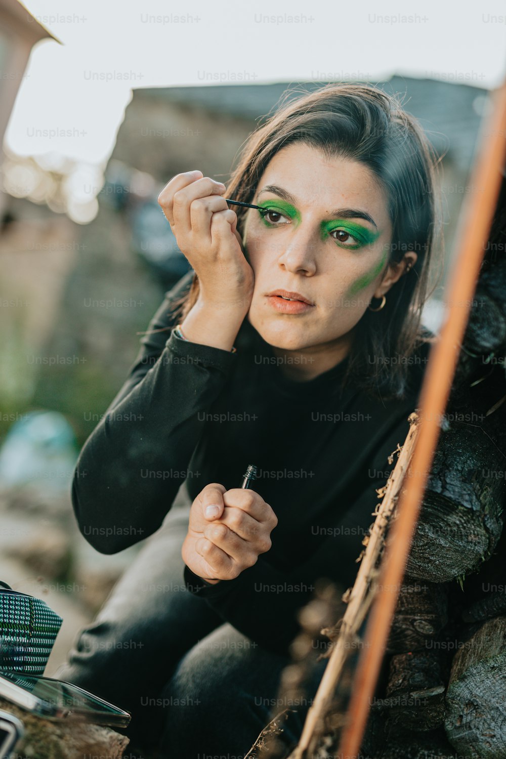 a woman with green makeup is sitting on the ground