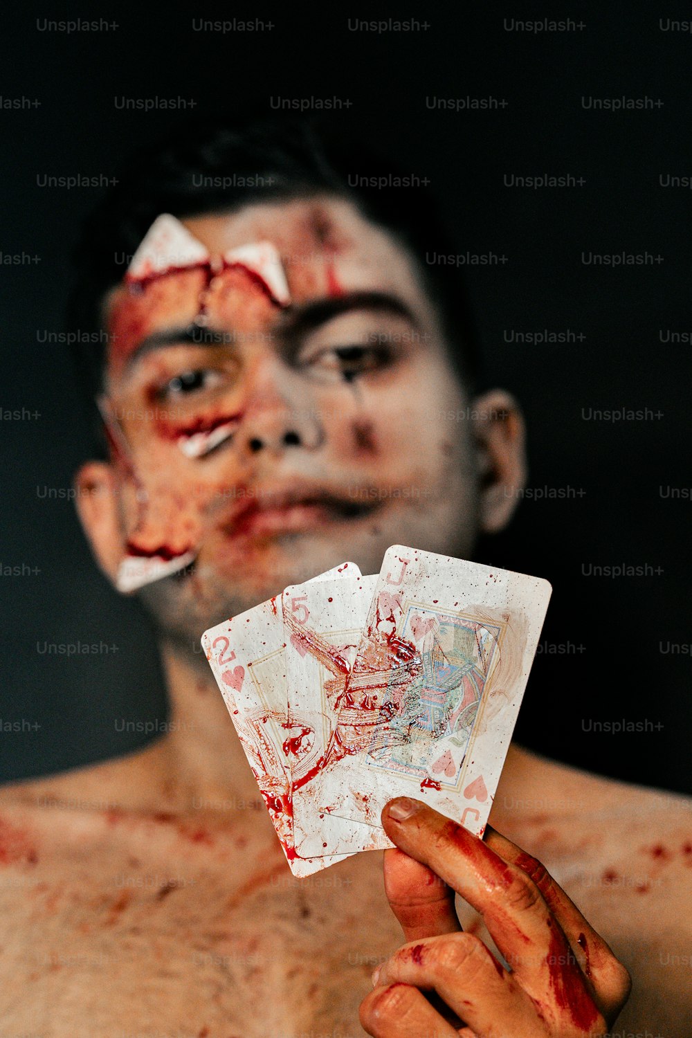 a man with blood all over his face holding a card