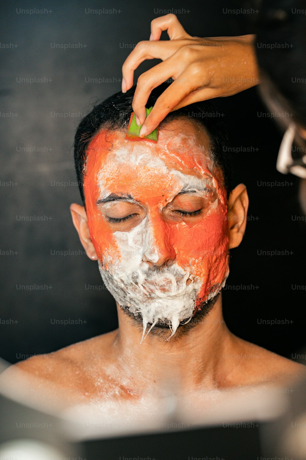 a man getting his face painted orange and white