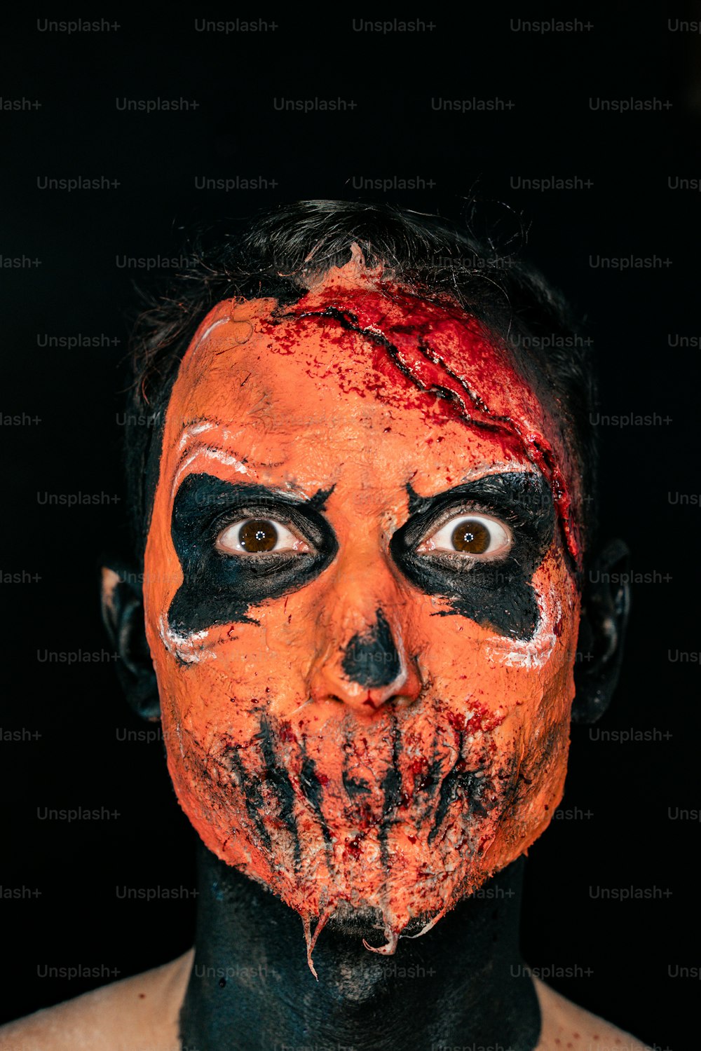 ein Mann mit orange-schwarz geschminktem Gesicht