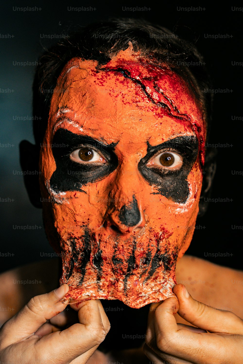 ein Mann mit orange-schwarz geschminktem Gesicht