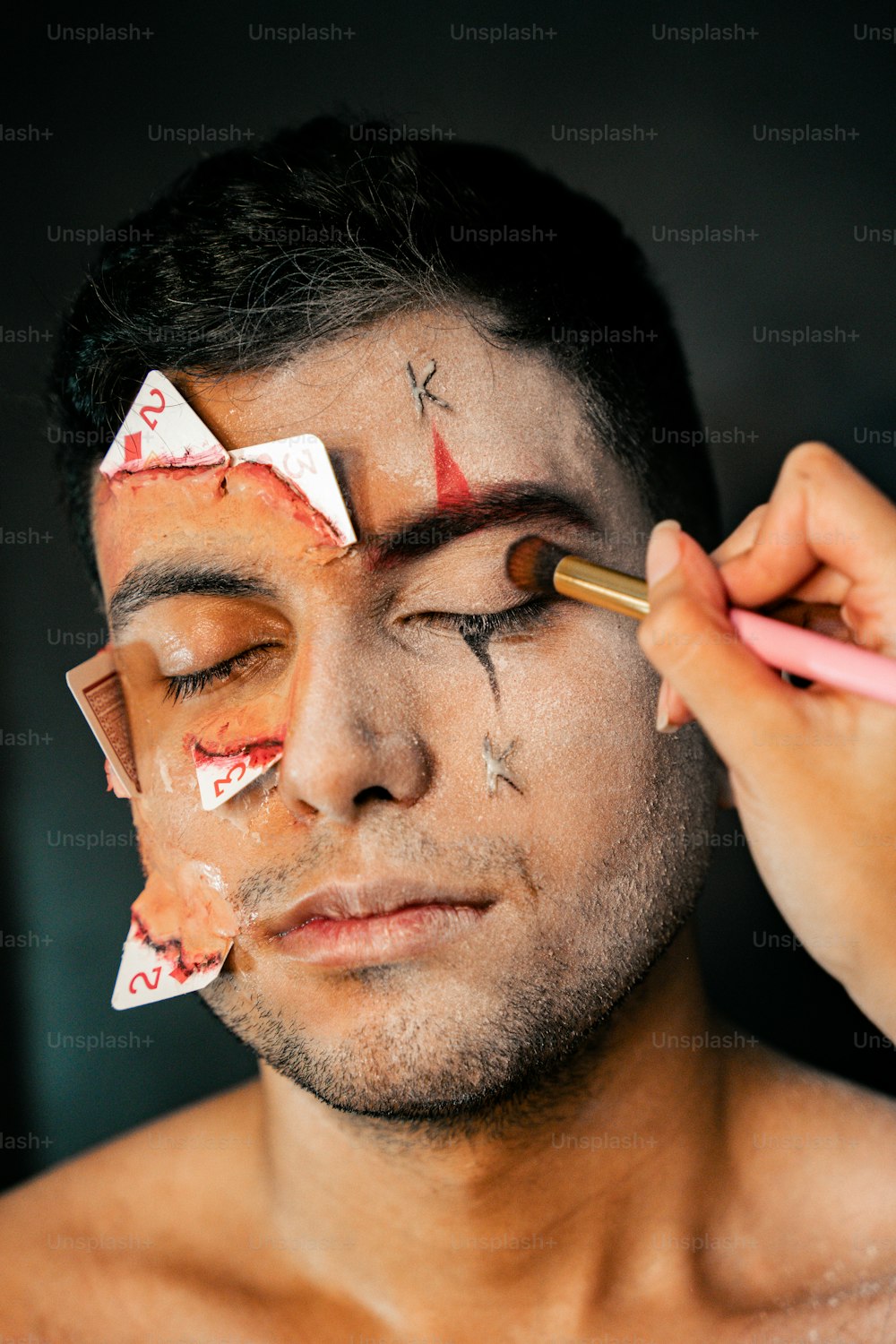 Ein Mann bekommt sein Gesicht mit Make-up bemalt