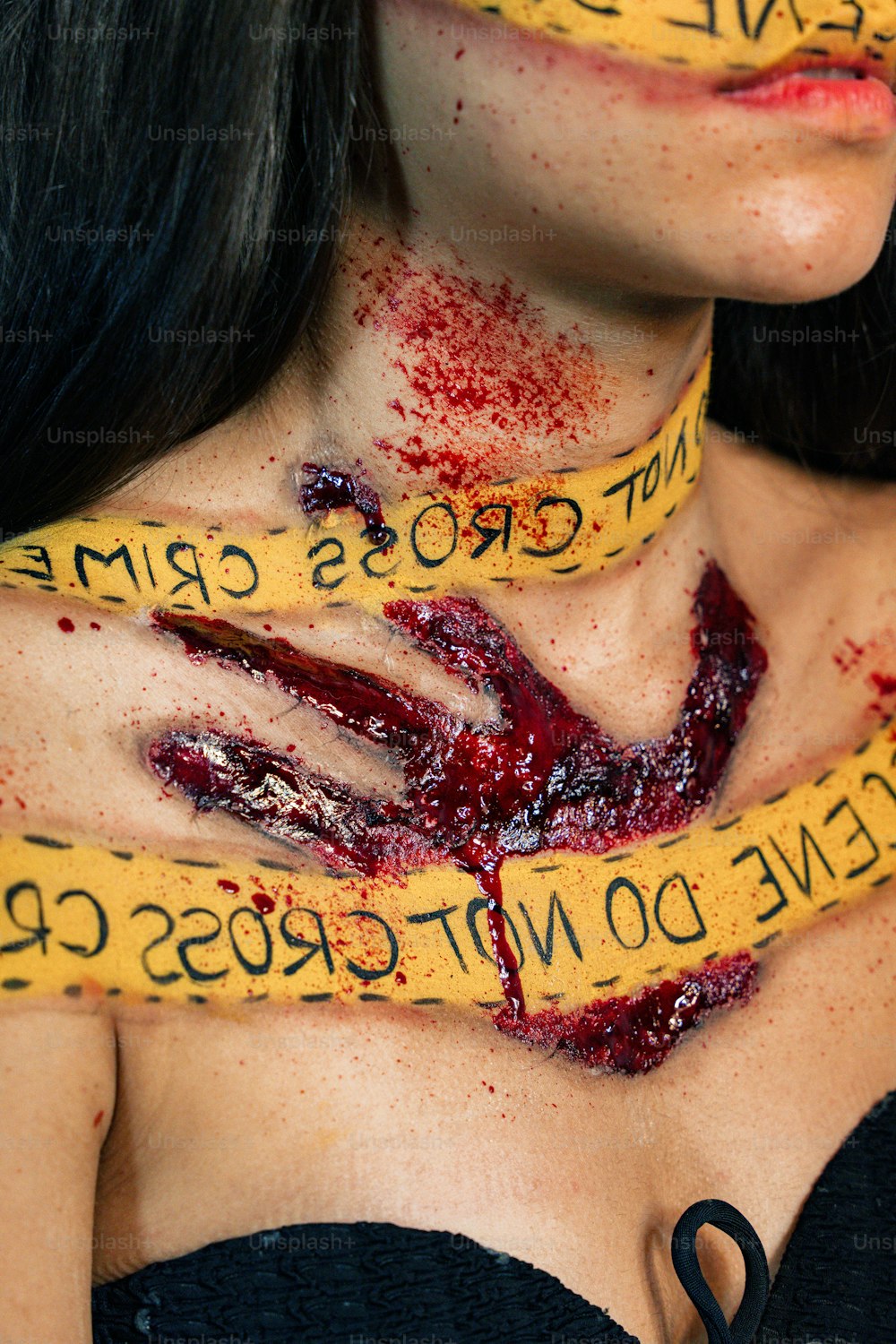 a woman with blood on her chest and yellow tape around her neck