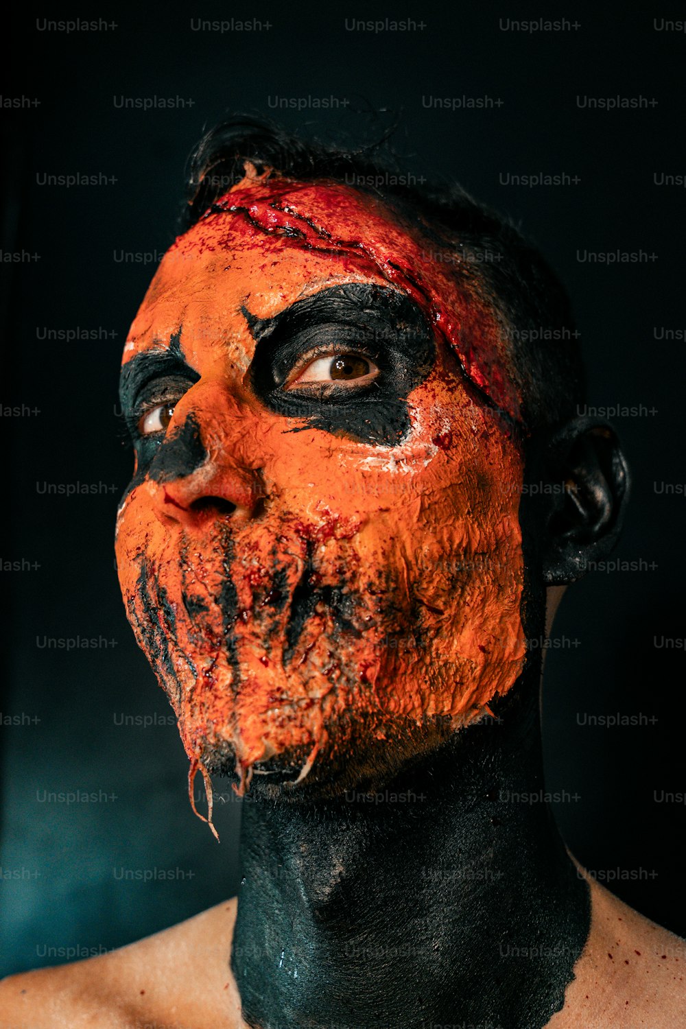 ein Mann mit schwarzer und orangefarbener Farbe im Gesicht