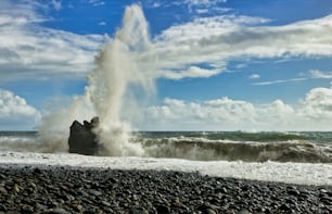 Una grande onda che colpisce su una spiaggia rocciosa