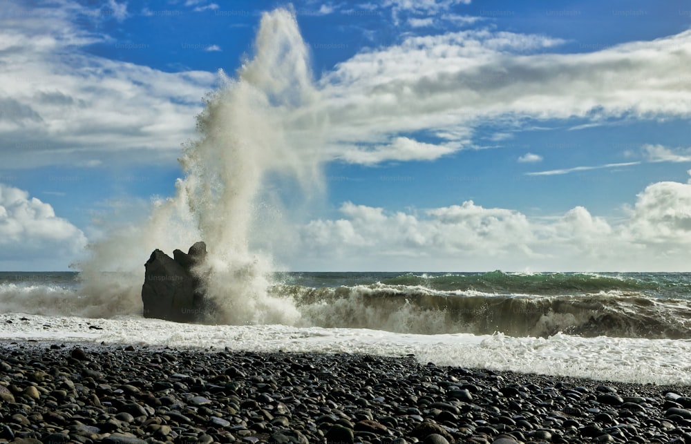 a large wave hitting on a rocky beach