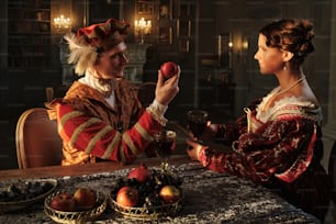 a man and a woman dressed in period costumes eating apples