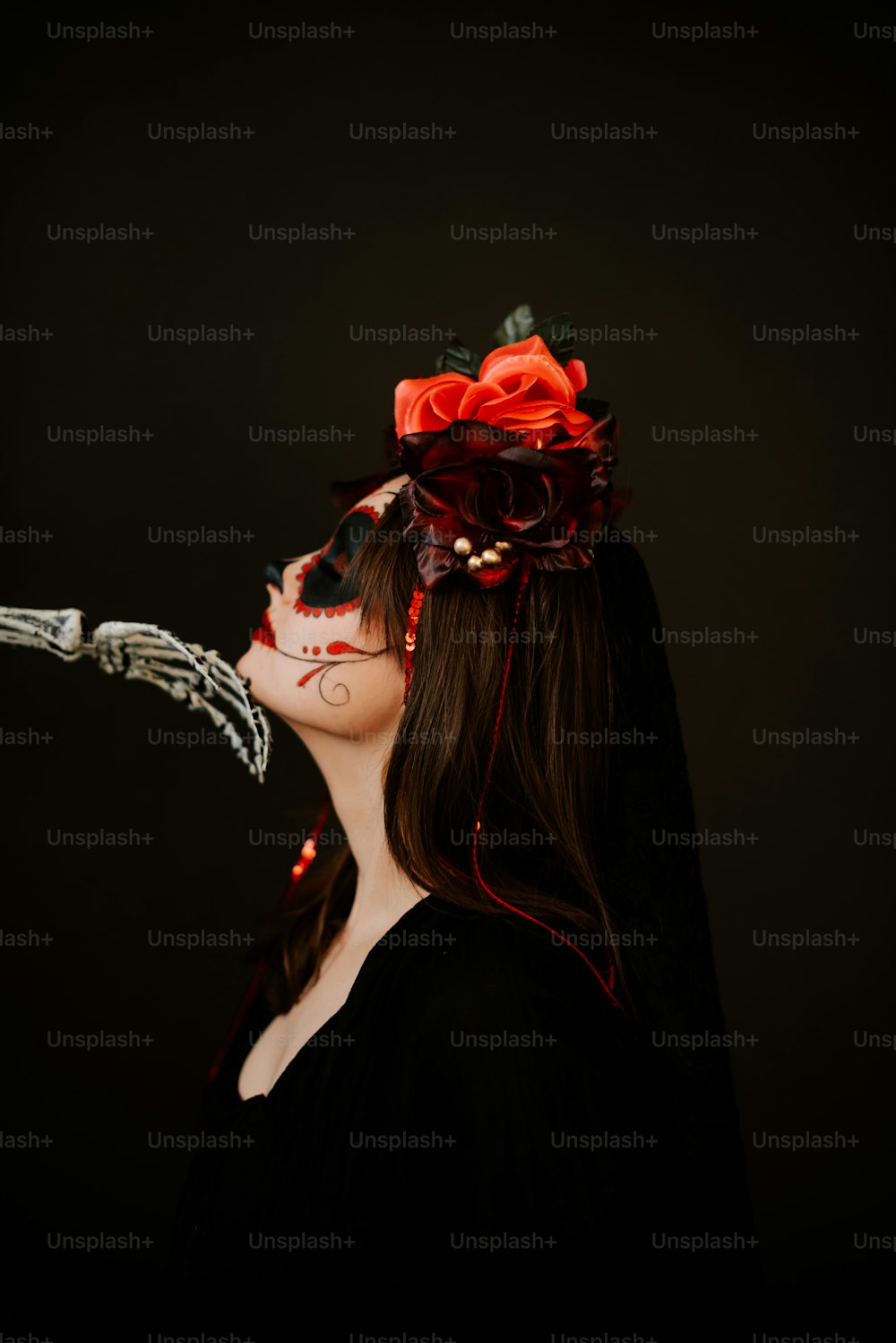 a woman wearing a skeleton mask and a red rose in her hair