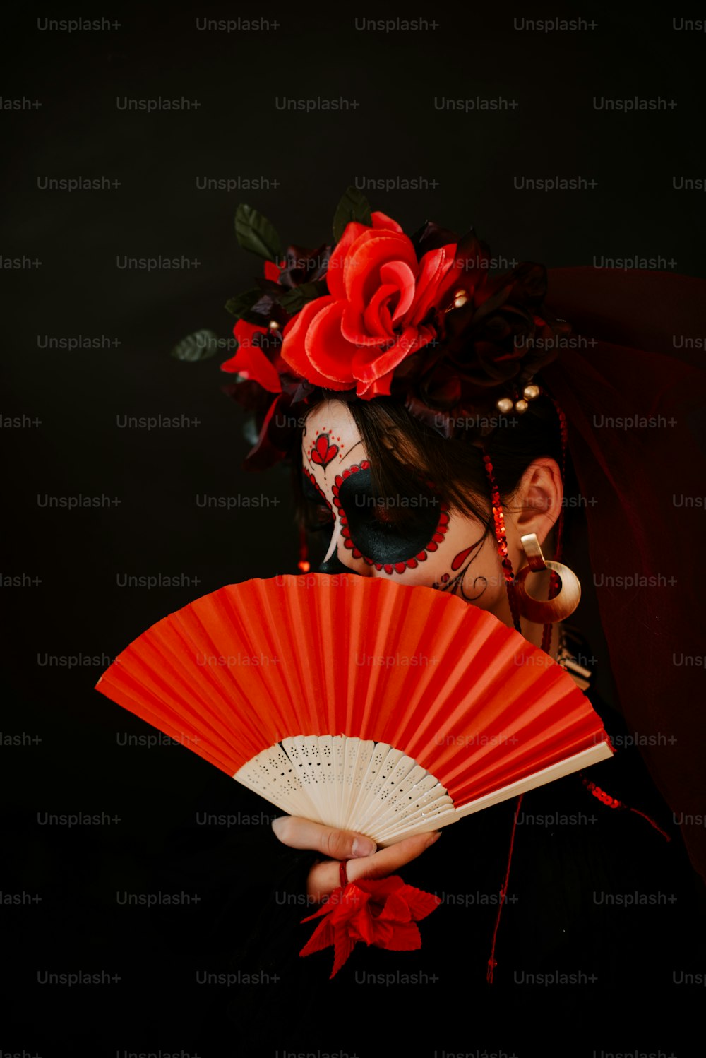 a woman with a red flower in her hair holding a red fan