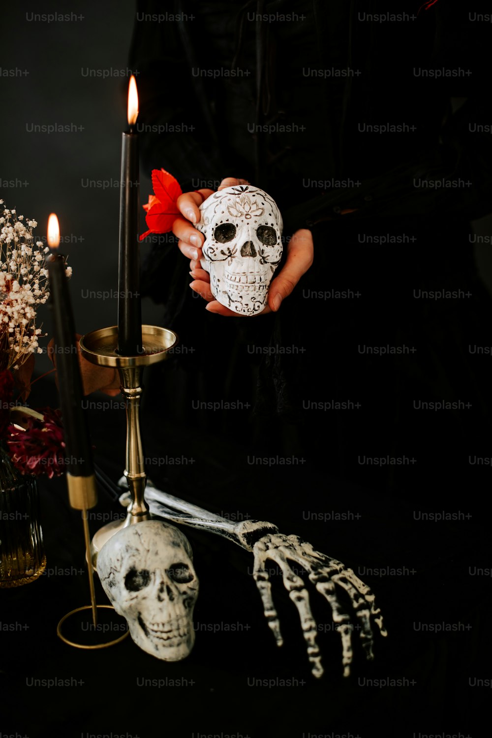 a person holding a skull in front of a candle
