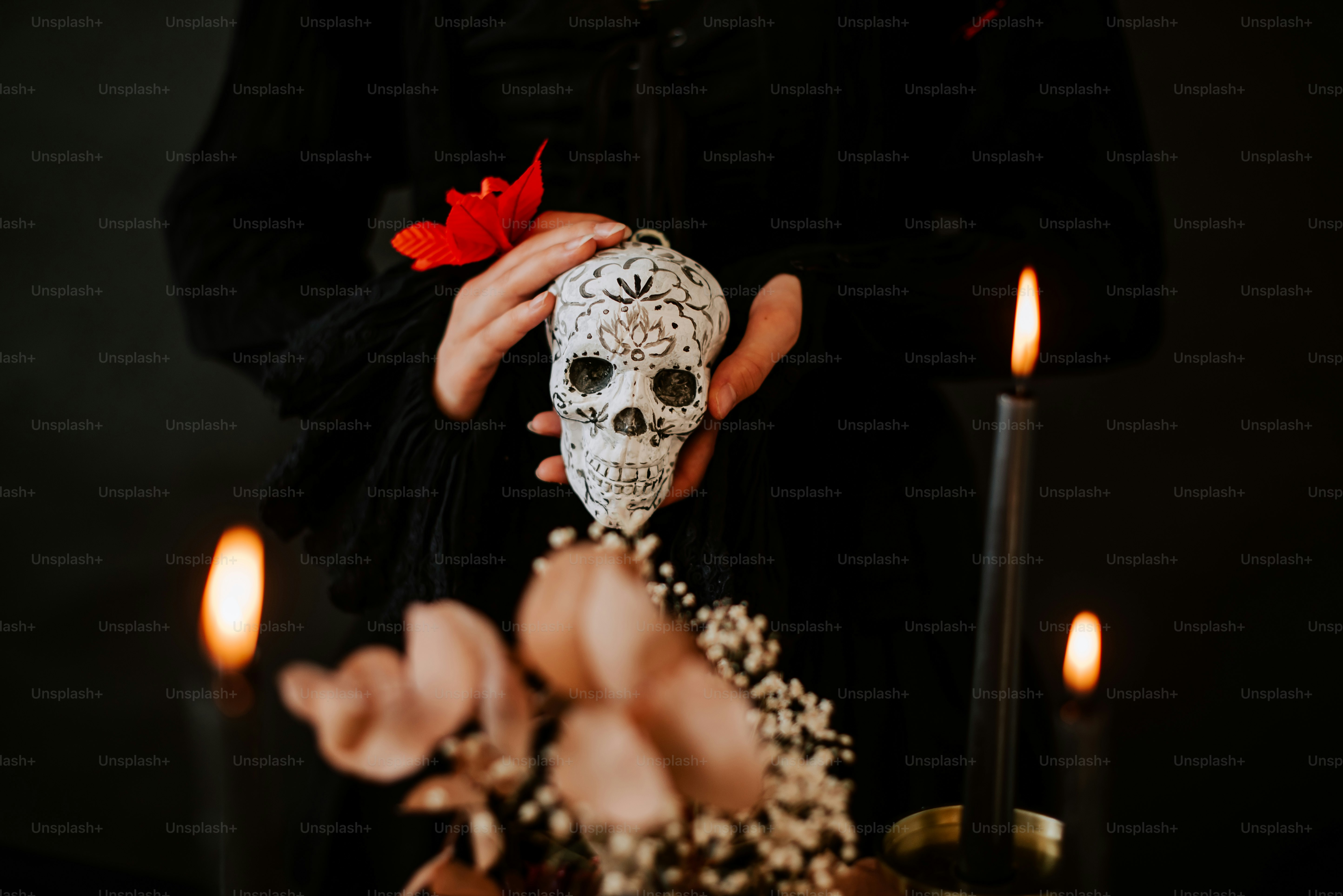 a person holding a skull in front of some candles