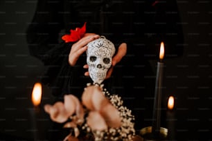 a person holding a skull in front of some candles