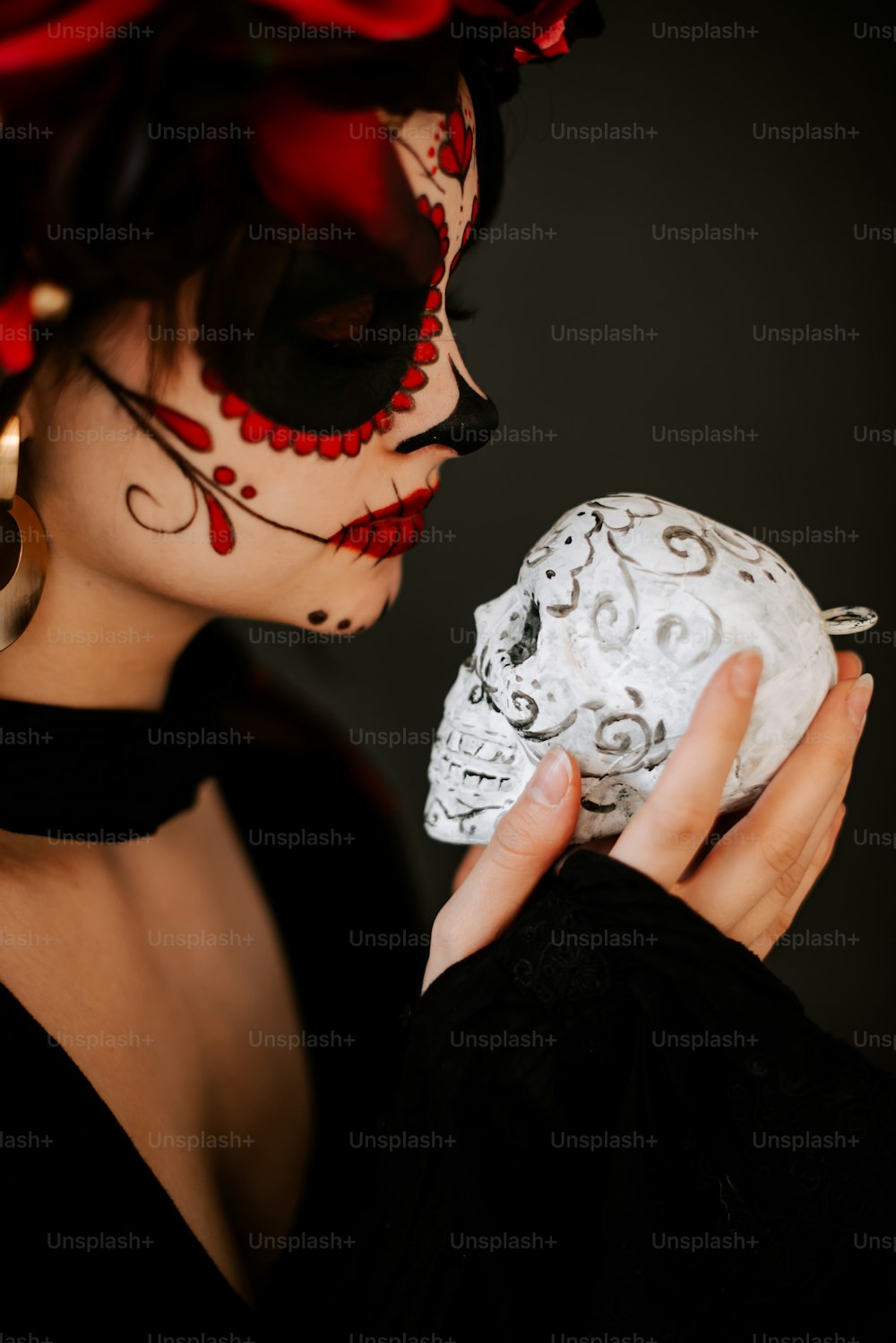 a woman in a black dress holding a white skull