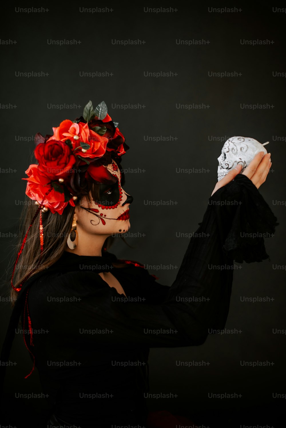 Una mujer con una máscara de calavera sosteniendo un pedazo de pastel