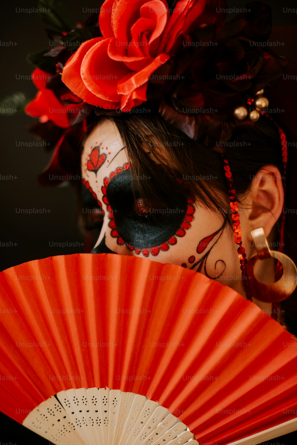 a woman with face paint holding a red fan