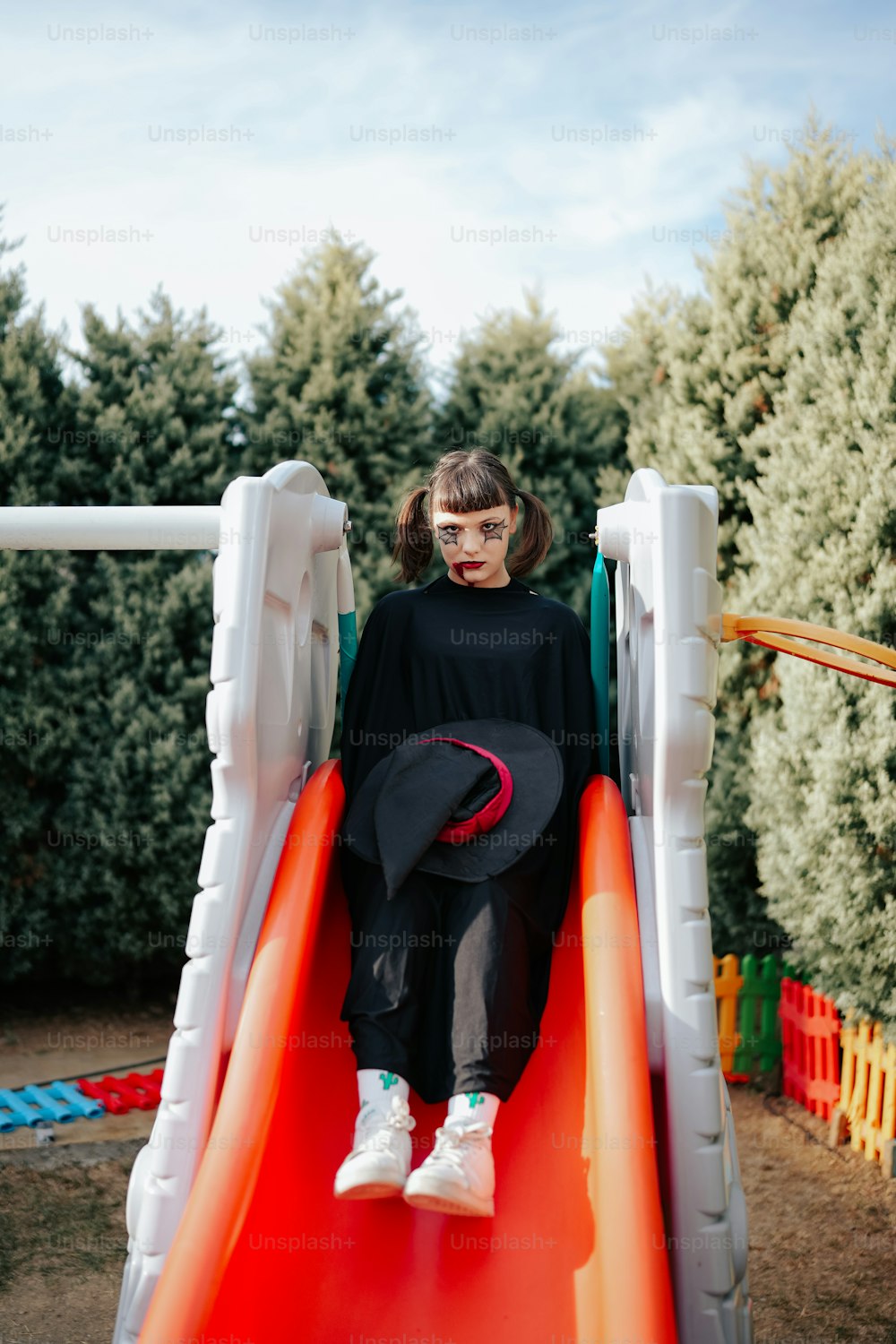 a little girl sitting on a slide with a hat on