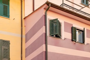 a pink and yellow building with green shutters