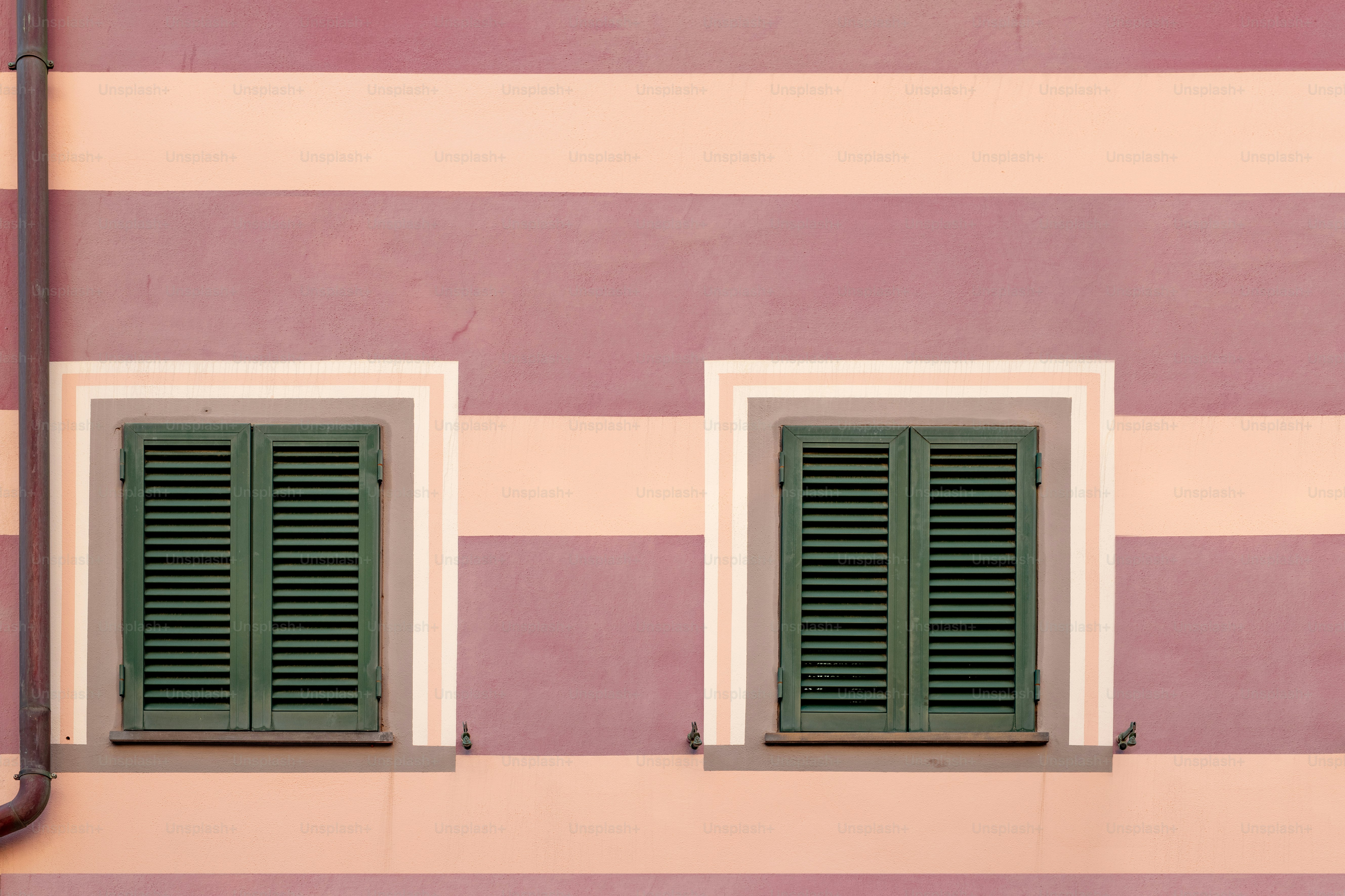 Duas persianas verdes em um edifício rosa e branco