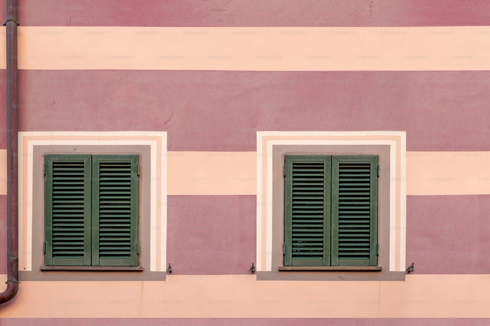 two green shutters on a pink and white building