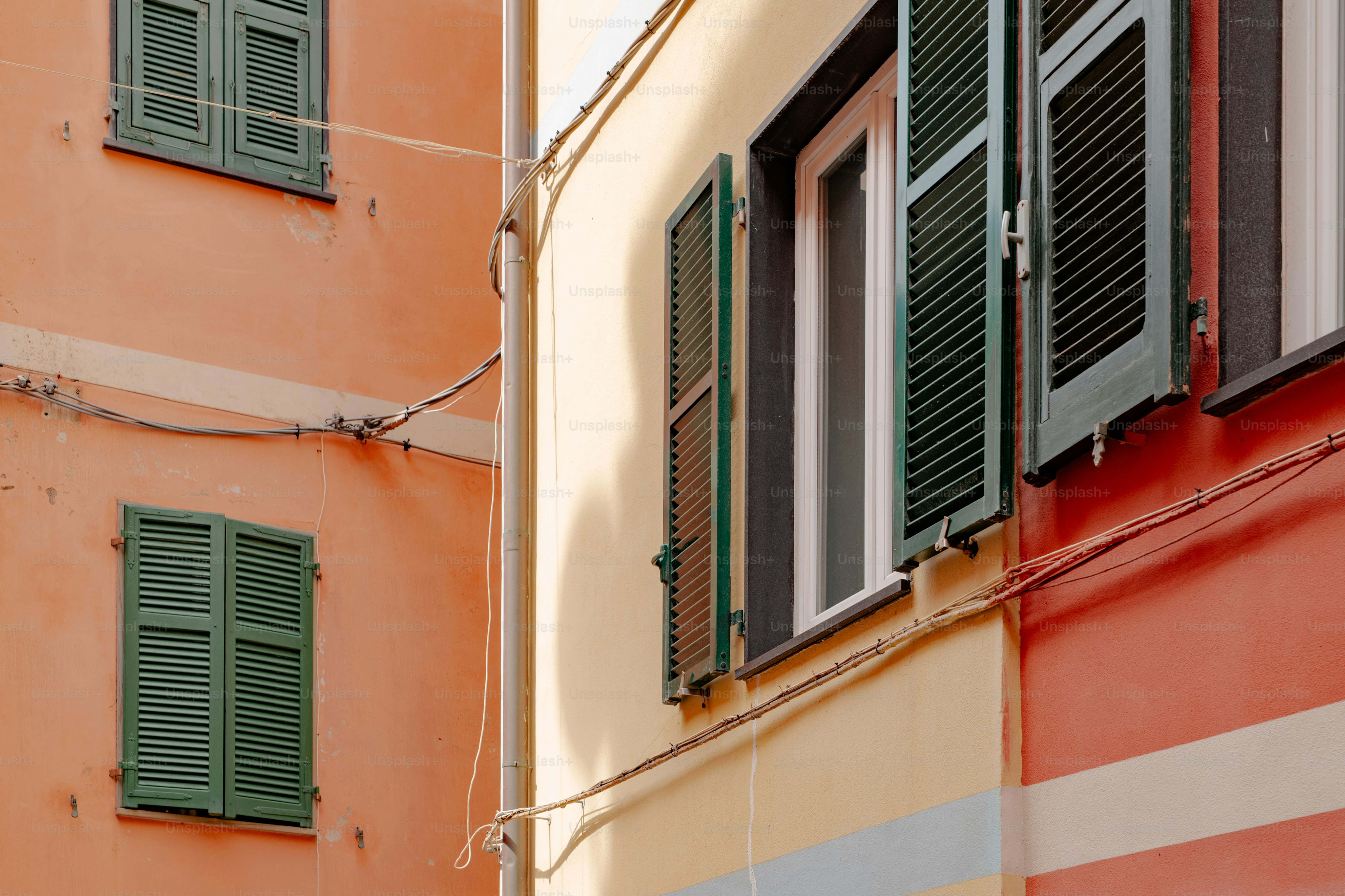 a building with green shutters and a red wall