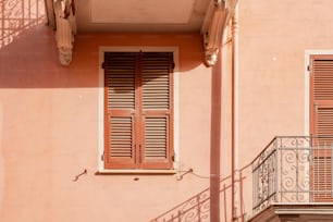 a pink building with a balcony and two windows