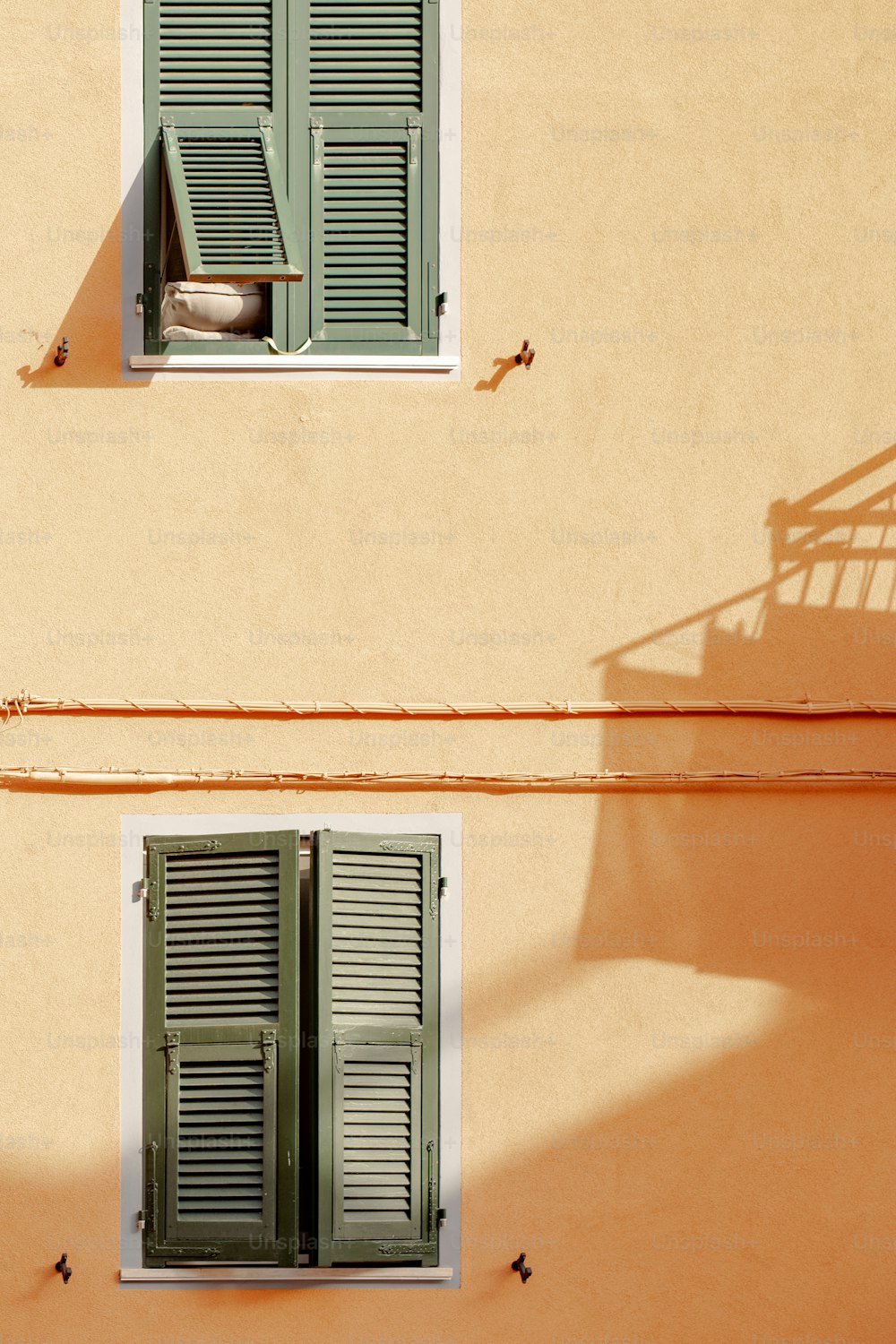 two windows with green shutters on a building