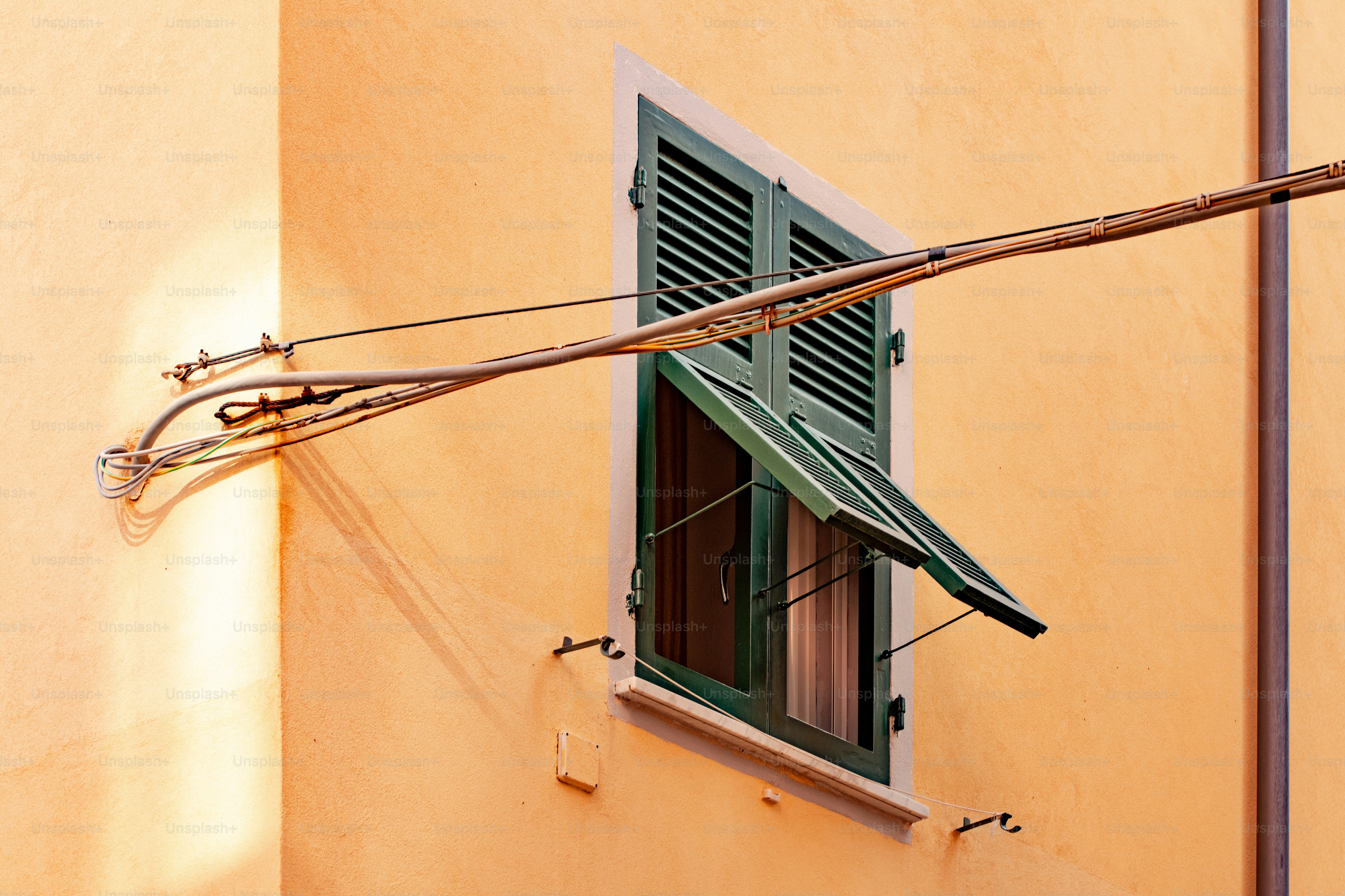 a yellow building with a green shutter and a window