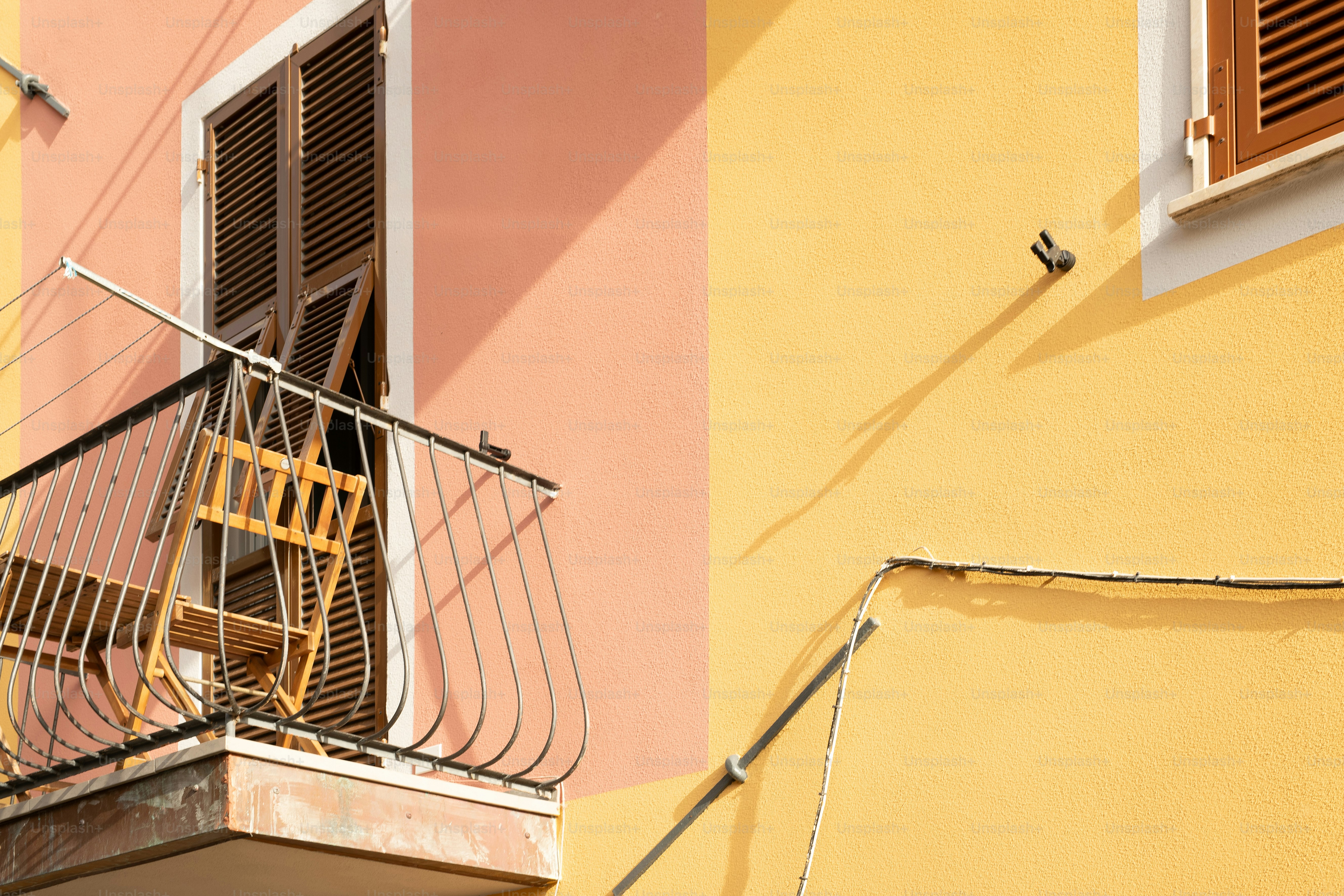 um edifício amarelo e rosa com uma varanda de madeira
