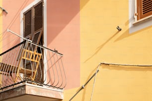 a yellow and pink building with a wooden balcony