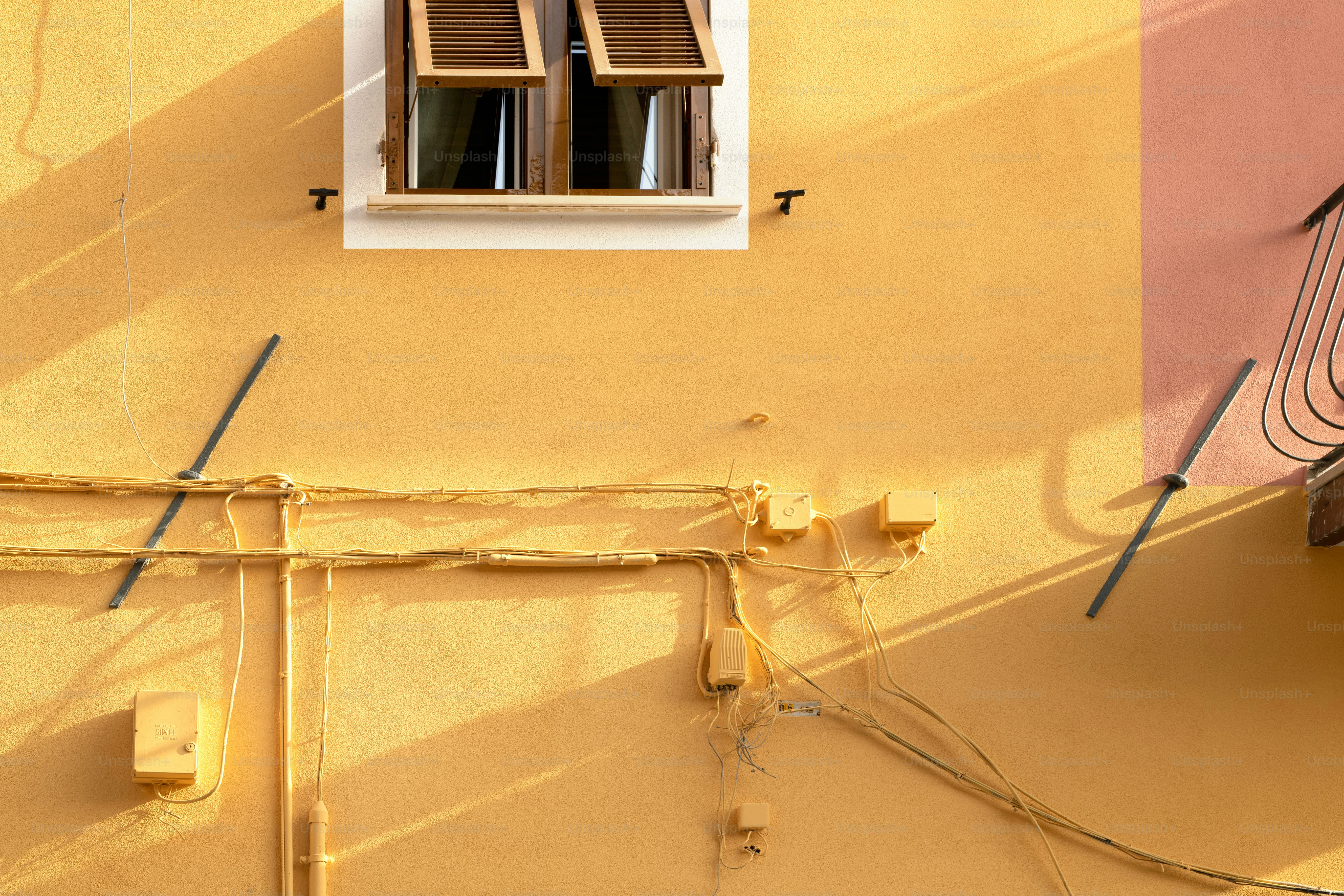 un mur jaune avec une fenêtre et des fils dessus